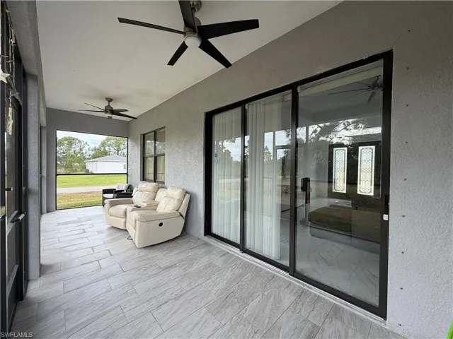 Sunroom with a textured wall, ceiling fan, and a patio area