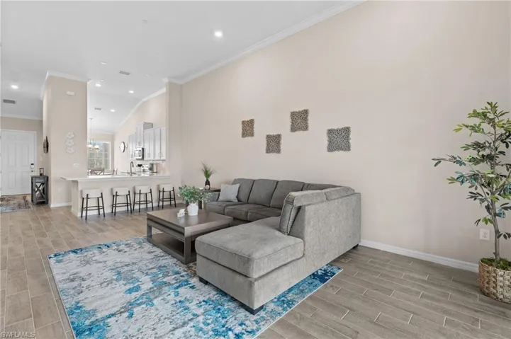 Living area with ornamental molding, wood tiled floor, baseboards, and recessed lighting