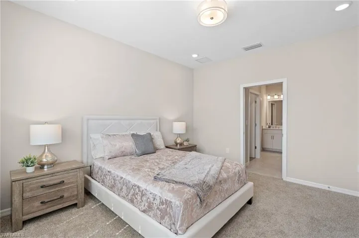 Bedroom with recessed lighting, visible vents, light carpet, connected bathroom, and baseboards