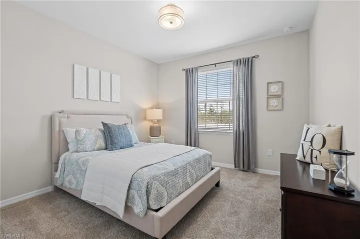 Bedroom with light colored carpet and baseboards