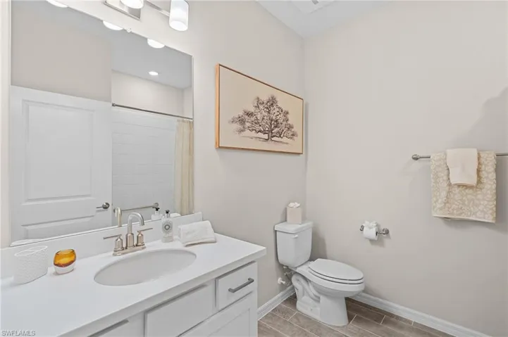Bathroom with toilet, a shower with curtain, baseboards, and vanity