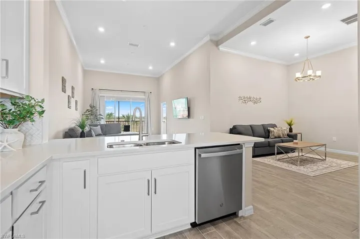 Kitchen with visible vents, white cabinets, appliances with stainless steel finishes, crown molding, and a sink