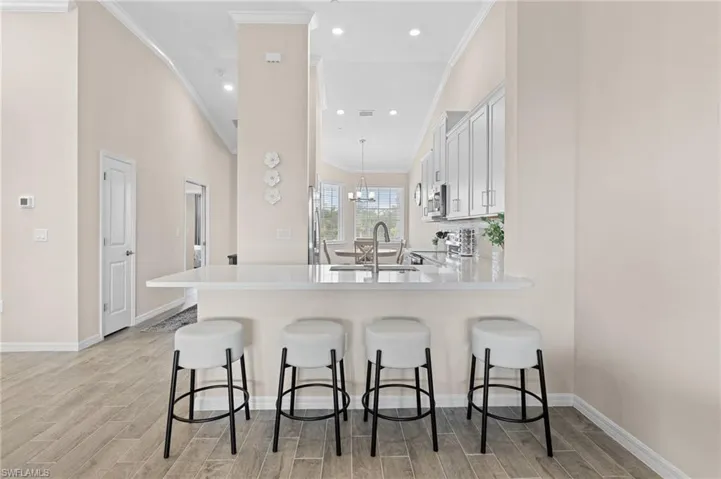 Dining area featuring wood tiled floor, ornamental molding, a chandelier, and baseboards