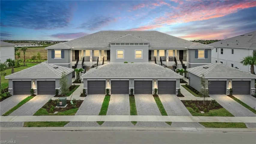 Townhome / multi-family property featuring driveway, a garage, stairway, a tiled roof, and stucco siding