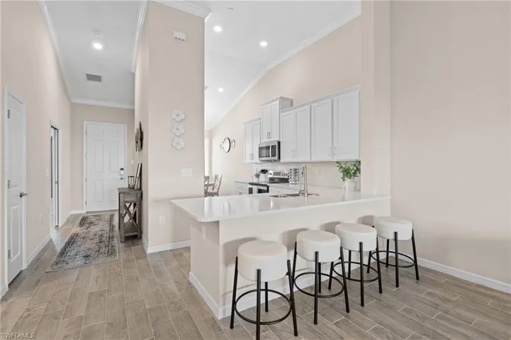 Kitchen featuring light countertops, a breakfast bar area, a peninsula, and white cabinetry