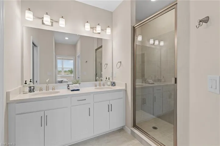 Ensuite bathroom with tile patterned floors, ensuite bath, a sink, and a shower stall