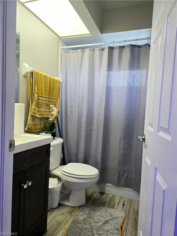 2nd Bathroom with tub, tile walls, and plank style tile flooring.