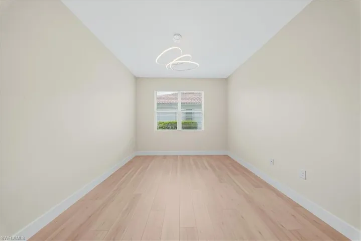 Empty room with light wood finished floors and a chandelier