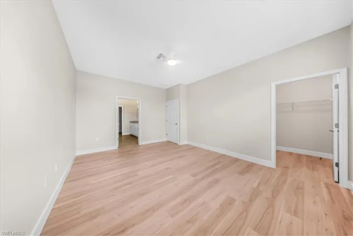Unfurnished bedroom with a walk in closet and light wood-style flooring