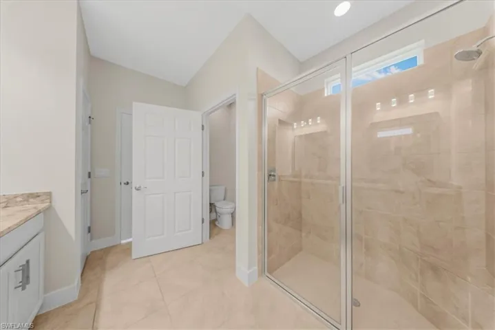 Full bathroom with a stall shower, vanity, and light tile patterned floors
