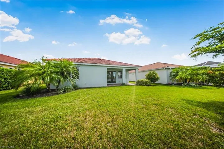 Rear view of property featuring stucco siding, a yard, and a tiled roof