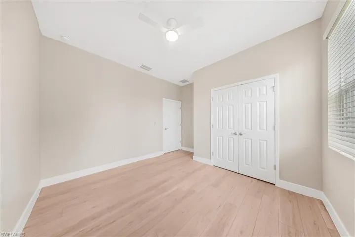 Unfurnished bedroom with light wood-style flooring, a closet, and a ceiling fan