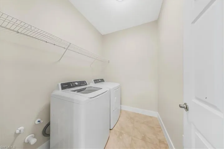 Laundry area featuring light tile patterned floors and washing machine and dryer