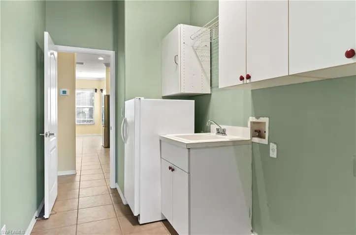 Laundry room with hookup for a washing machine and dryer, utility sink, cabinet space, and light tile patterned floors