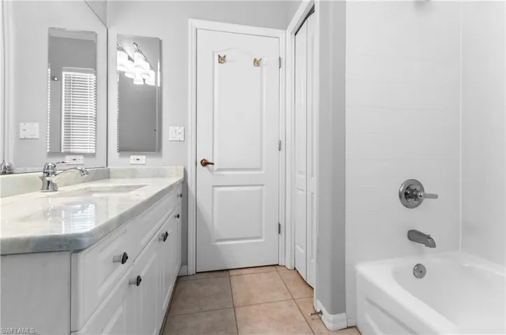 Guest bathroom featuring vanity, light tile patterned floors, and tub / shower combination