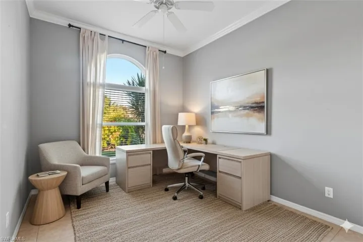 2nd bedroom virtually staged as home office with ornamental molding, ceiling fan, and light tile patterned floors