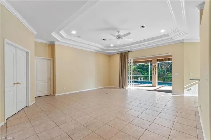 Room with crown molding, a ceiling fan, light tile patterned floors, a tray ceiling, and recessed lighting