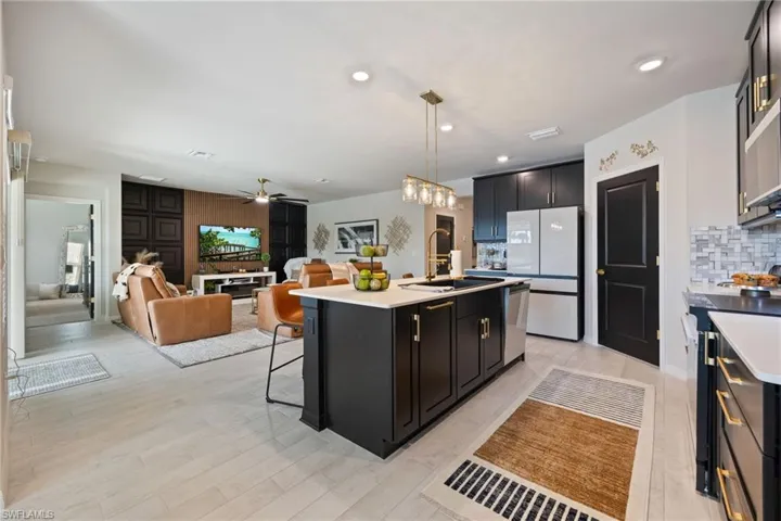 Kitchen featuring dark cabinetry, decorative light fixtures, decorative backsplash, freestanding refrigerator, and recessed lighting