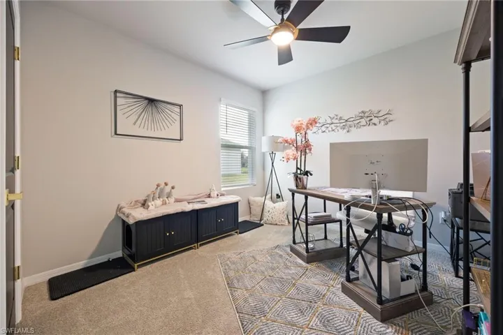 Carpeted office space featuring a ceiling fan and baseboards