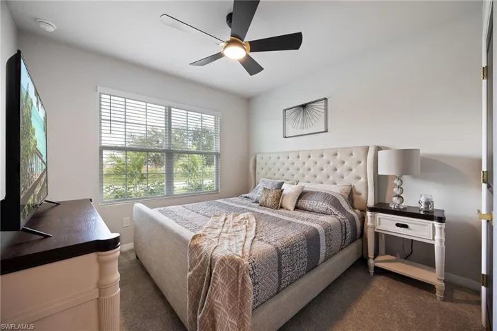 Carpeted bedroom featuring ceiling fan and baseboards
