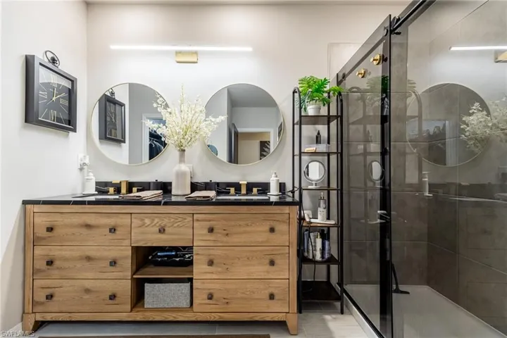 Bathroom featuring double vanity, a stall shower, and tile patterned flooring
