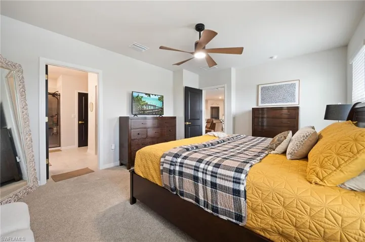 Bedroom with carpet floors, ceiling fan, and ensuite bathroom