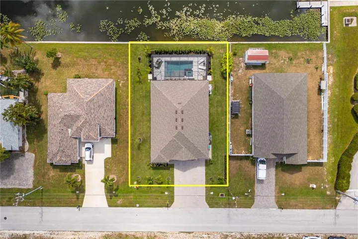 Aerial view of residential area with property parcel outlined and a large body of water
