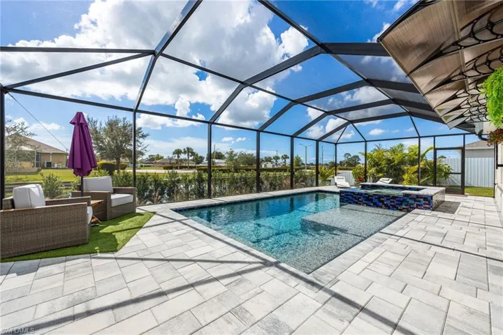 View of swimming pool with glass enclosure, a sunroom, a pool with connected hot tub, and a patio area