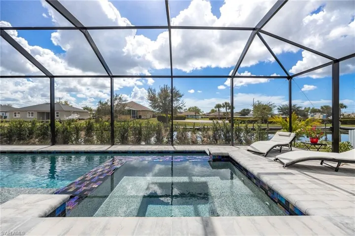 View of pool with a sunroom, glass enclosure, a water view, and a pool with connected hot tub