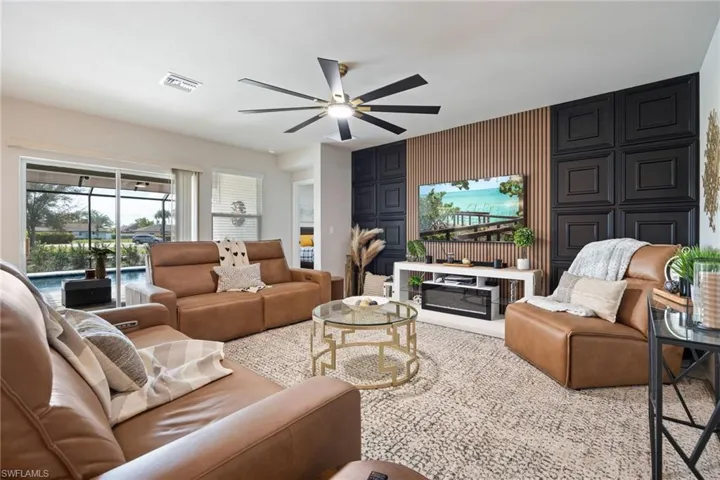 Living room featuring ceiling fan, an accent wall, and wood walls