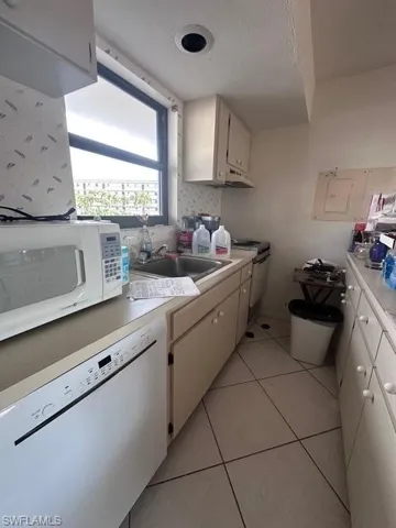 Kitchen with light countertops, white appliances, a sink, and white cabinetry