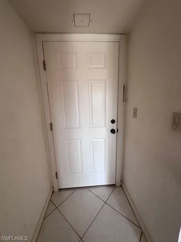 Doorway to outside with light tile patterned flooring and baseboards