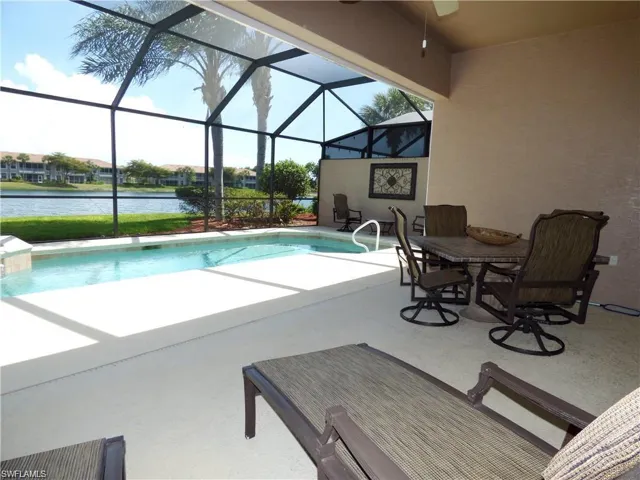 View of swimming pool featuring glass enclosure, a patio area, and a water view