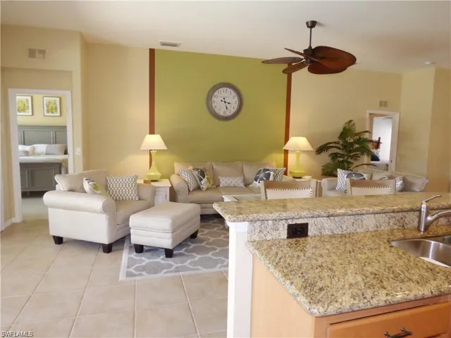 Living room featuring ceiling fan, sink, and light tile patterned floors