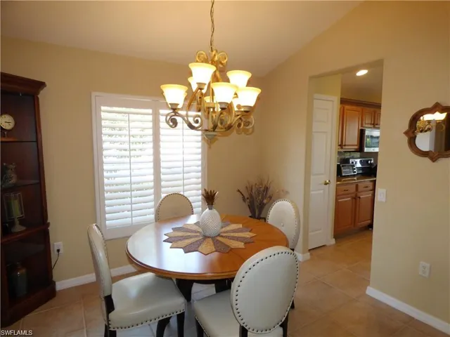 Tiled dining area featuring an inviting chandelier and lofted ceiling