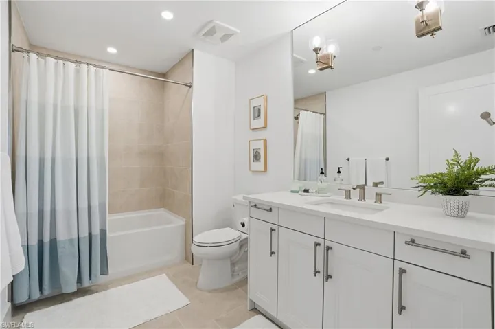 Bathroom featuring vanity, shower / bath combination with curtain, light tile patterned floors, and recessed lighting - Virtually Edited Image