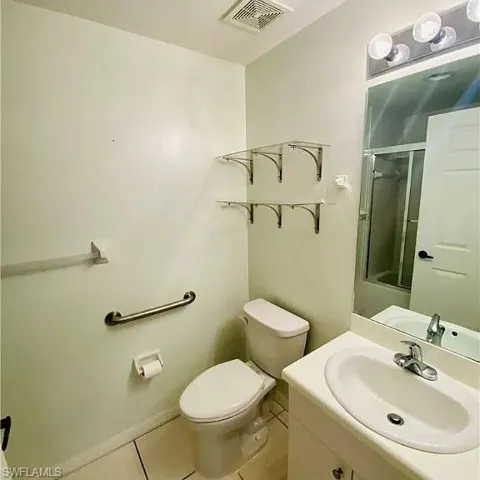 Full bathroom featuring a shower with door, vanity, and light tile patterned flooring