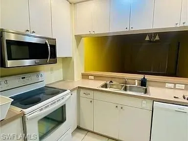 Kitchen with white appliances, light countertops, white cabinets, and light tile patterned flooring