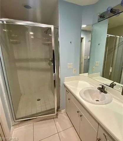 Bathroom with vanity, light tile patterned flooring, and a shower stall