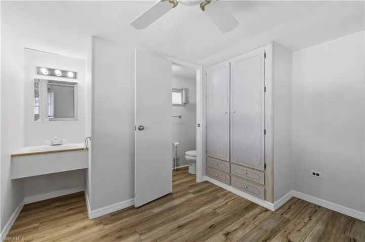 Unfurnished bedroom featuring light wood-style floors, ceiling fan, and ensuite bathroom