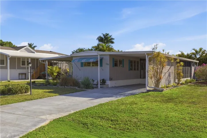 View of front facade with an attached carport, concrete driveway, and a front lawn