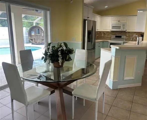 Dining area with lofted ceiling and light tile patterned flooring