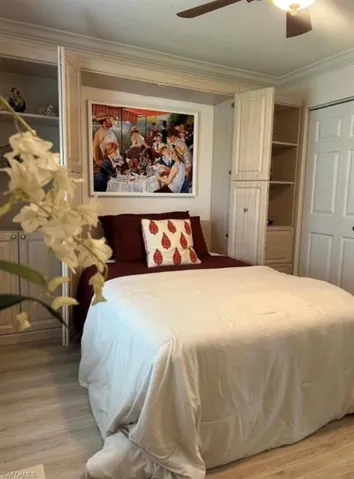 Bedroom with ornamental molding, light wood-style floors, ceiling fan and Murphy bed
