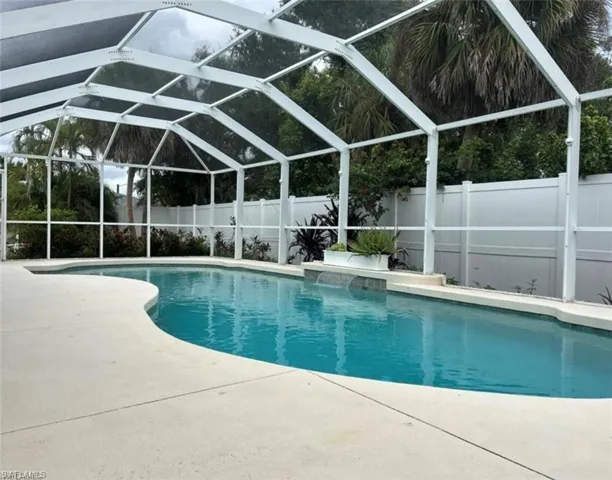 View of pool with screened enclosure and a fenced backyard