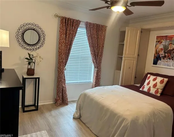 Bedroom with wood finished floors, crown molding, and ceiling fan