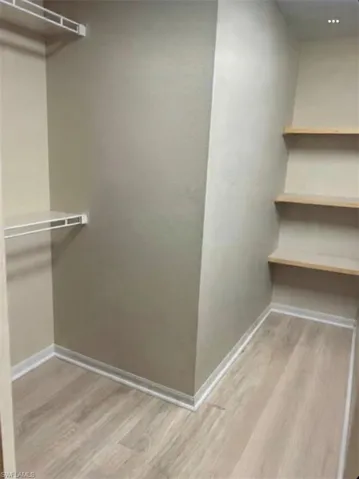 Walk in closet with light wood finished floors