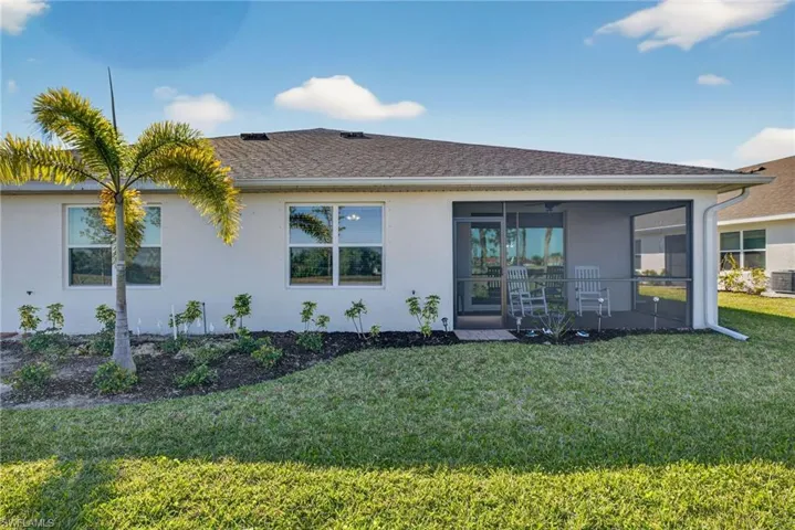 Rear view of property with stucco siding, a yard, a shingled roof, and a lanai