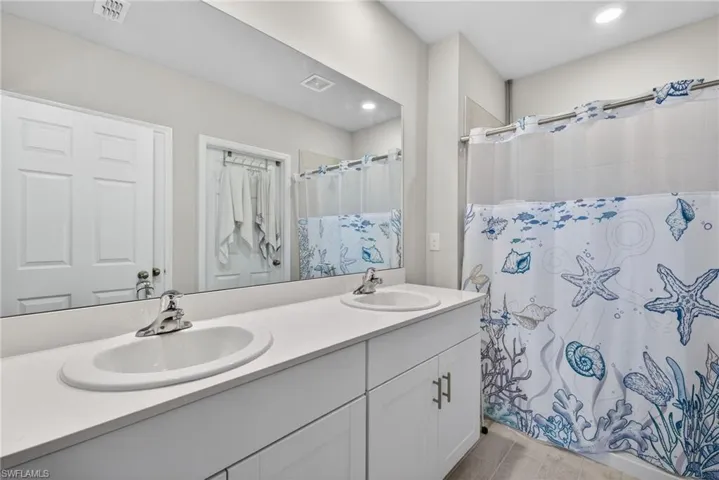 Full bathroom featuring double vanity and a shower.