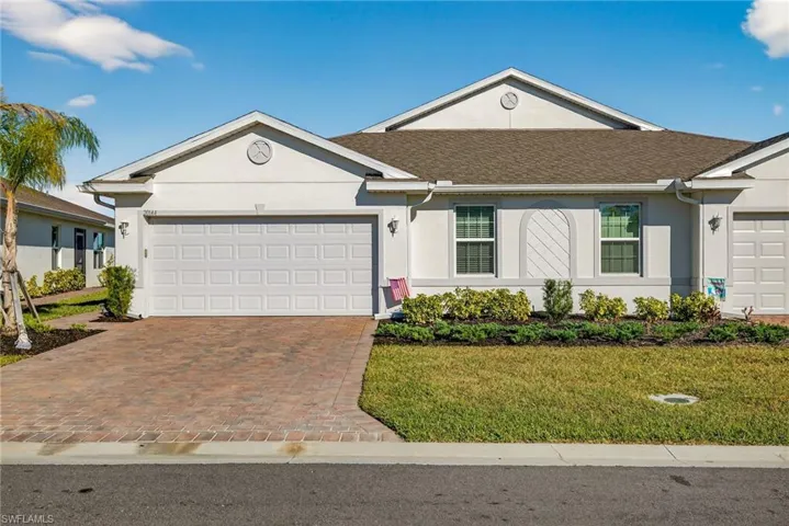 Single story home with an attached garage, stucco siding, a front lawn, and decorative driveway