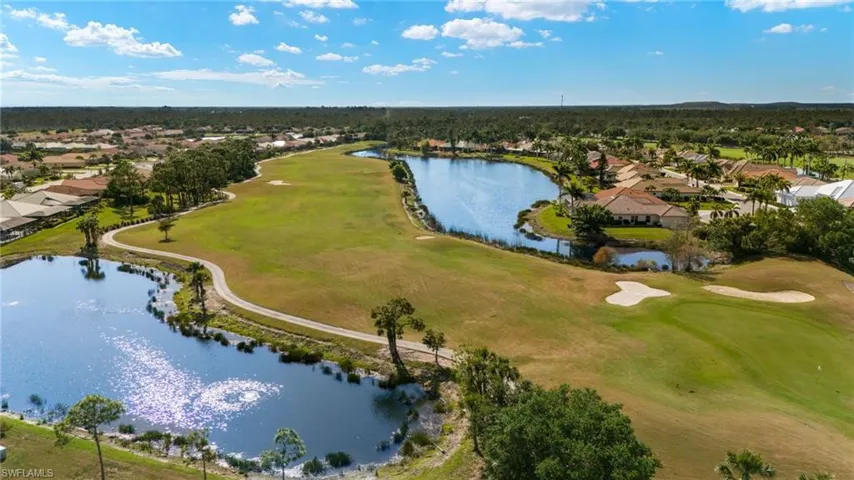 Aerial view of residential area featuring a nearby body of water and a golf club